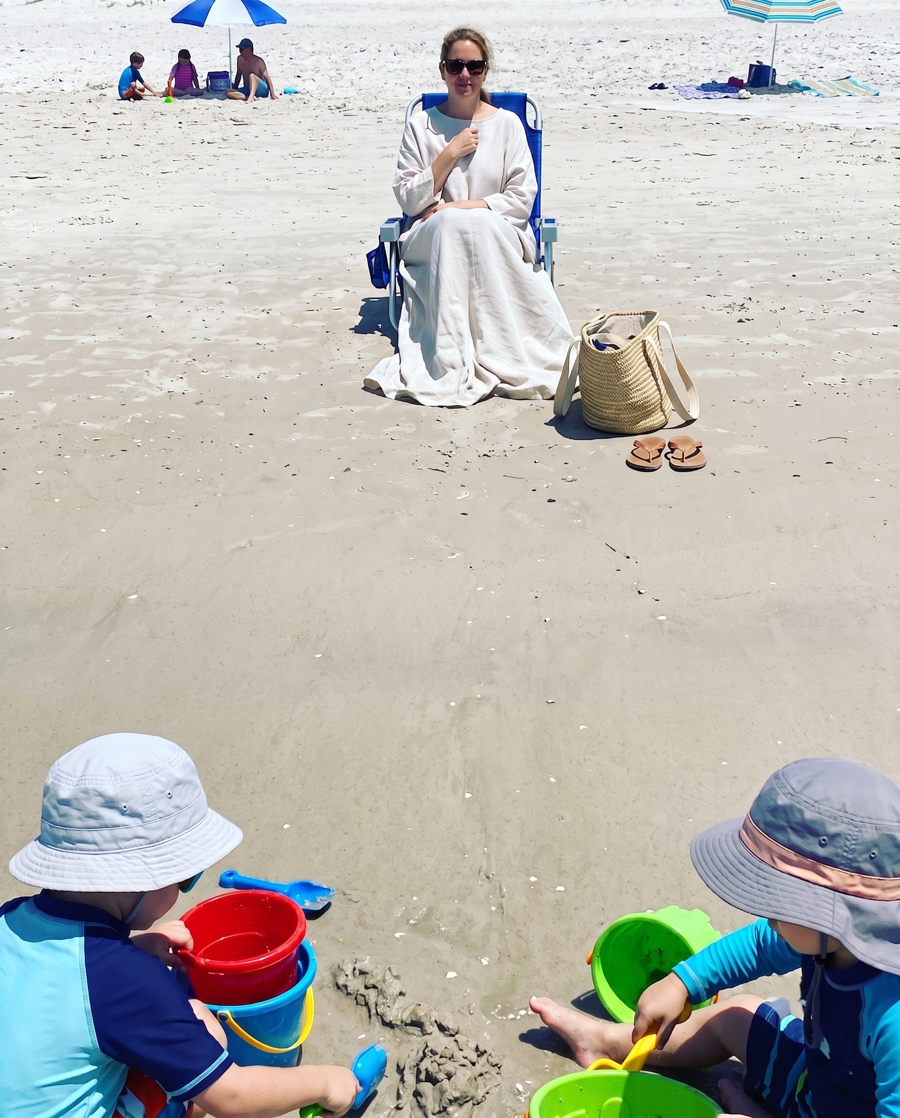 Dana on the beach, wrapped head to toe in a cover-up, watching her two kids play in the sand